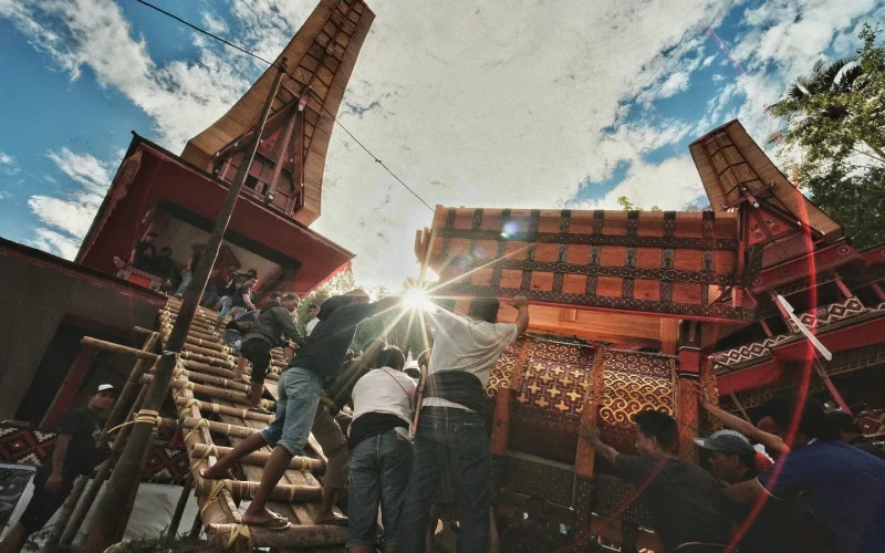 Guests climbing bamboo steps into a ceremonial ground during a rambu solo funeral in Tana Toraja