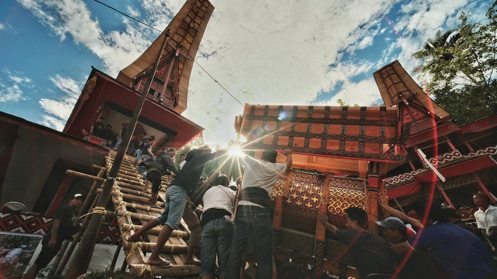 Guests climbing bamboo steps into a ceremonial ground during a rambu solo funeral in Tana Toraja