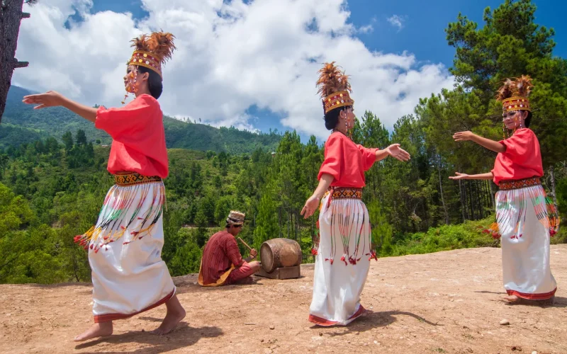 Dancers in traditional Toraja dress performing the pa'gellu dance on a highland ridge