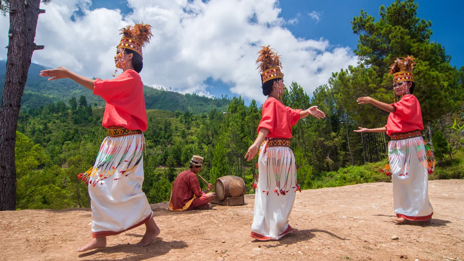 Dancers in traditional Toraja dress performing the pa'gellu dance on a highland ridge