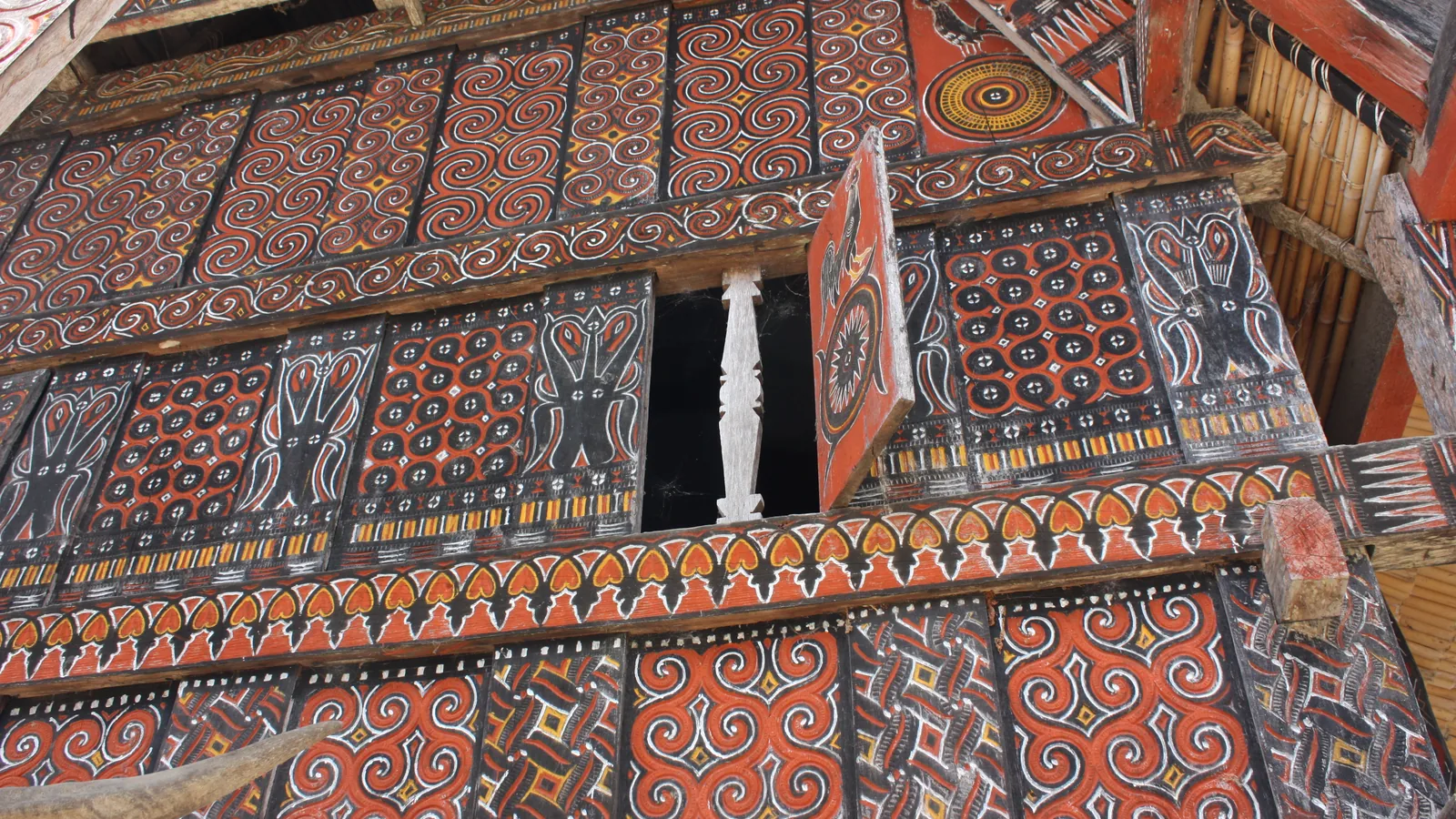 Carved and painted pa'ssura panels on a tongkonan facade at Palawa, the motifs used on Toraja crafts